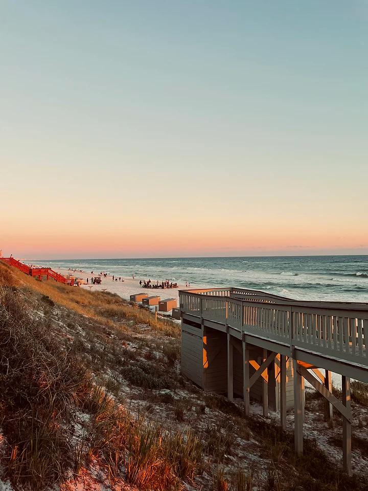 A boardwalk running along a dune above the sea at last light.