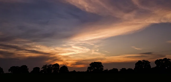 A wide band of gold and grey cloud stretched low over a dark horizon.