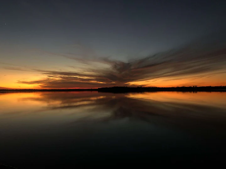 A sunset mirrored almost perfectly in absolutely still water.