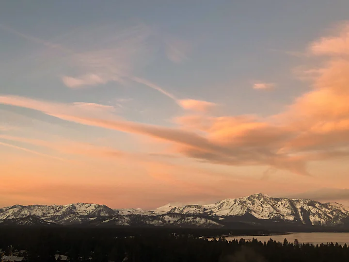 Snow-capped peaks under soft pink cloud at the end of the day.
