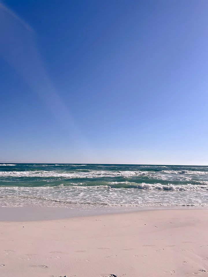Clear turquoise surf running up a bright, empty stretch of sand.